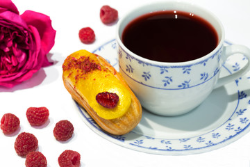 Fruit yellow eclair cake with hibiscus tea ( Sudan rose tea), served with raspberry and pink roses.