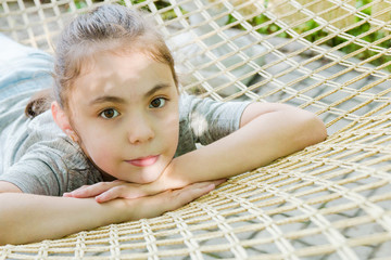 Cute little girl is lying in the hammock and have a rest