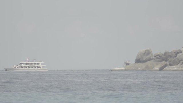 Scenic view of the sea and rocky island from the shore. Boats float on the sea waves. S-log, ungraded