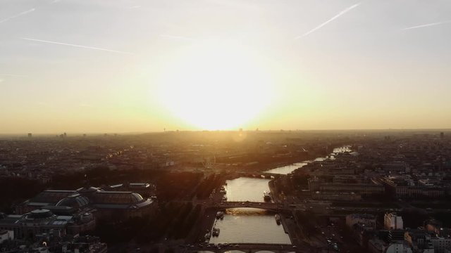 The sun rises over Paris. The river Seine and the famous city is painted in golden light.