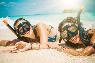 Two happy girlfriends with snorkeling mask enjoying on the beach - obrazy, fototapety, plakaty