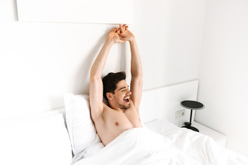 Fototapeta na wymiar Happy shirtless man stretching his hands while laying