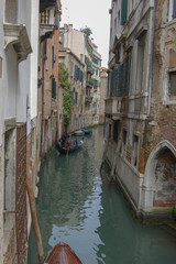 Fototapeta na wymiar Classic view of a narrow back cana with gondola and leaning buildings, Venice, Italty