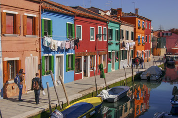 Fototapeta na wymiar Colourful houses and bustling and busy canals on the fishing village of Burano in the Venice Lagoon, Italy