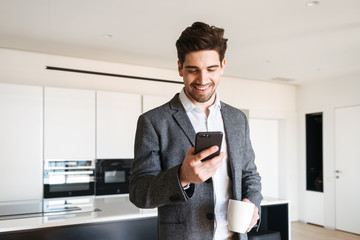 Happy young man in suit looking at mobile phone