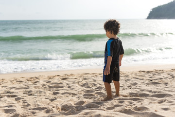 Kid wearing a swimming suit and looking to the sea