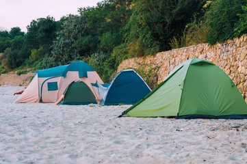 Tent town of tourists on the beach against the background of the rock. The concept of tourism.