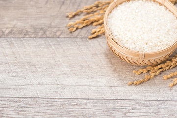 Close up raw rice and unmilled rice in traditions bamboo basket on wooden background, copy space(text space), blank for text