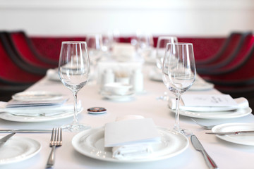 Perspective view of table set with white dishware and crystal clear wineglasses on white tablecloth