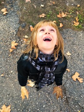 Boy with gold hair, playing with autumn lefs outside