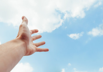 the human hand stretches to the blue sky
