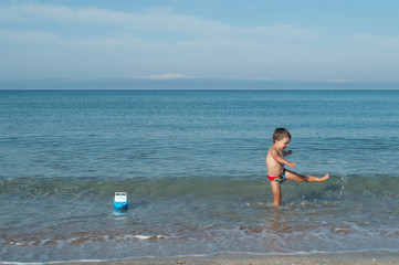 the kid is playing in the sea. the child dances with happiness.