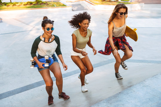 Three smiling young girls with skateboards