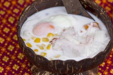 Dumplings in coconut cream (Bua Loi) and coconut meat with egg in coconut shell on Thai silk, Dessert of Thailand.