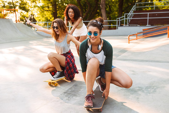 Three smiling young girls with skateboards