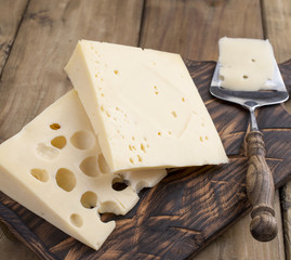 A beautiful Swiss cheese with holes, a useful dairy product. Tasty food. Country style photo. Place for text. Copy space.