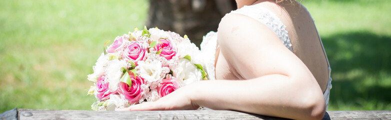 The bride sits on a bench with a bouquet