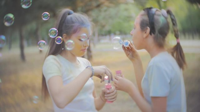 Two girls get dirty with dry colors Holi blow soap bubbles