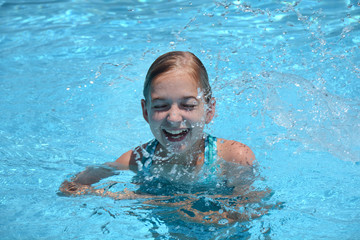 young girl laughing and splashing in swimming pool