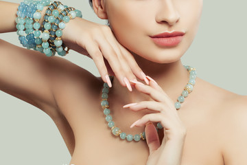 Jewelry on female hand. Natural color nails, pink lips and blue bracelet