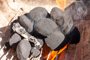 Barbecue charcoal briquettes alight on the bottom of the BBQ