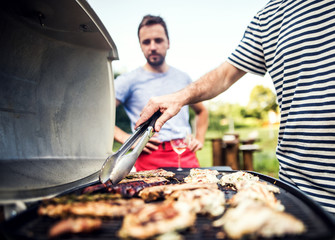 Unrecognizable man cooking seafood on a barbecue grill in the backyard. Close up.
