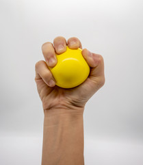 Hand holding yellow stress ball isolated on white