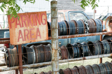 Sign Parking area, old tires on vintage car junk yard