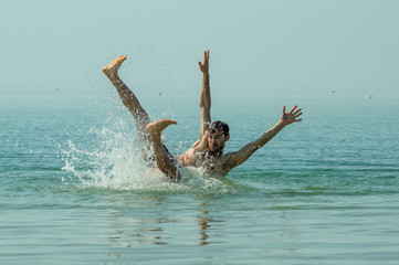 A young guy falls into the sea water, a beautiful spray