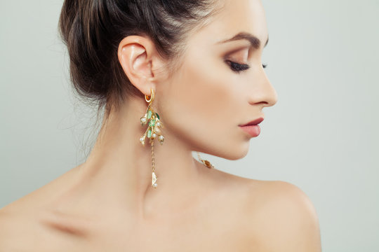 Attractive Woman Wearing Gold Earrings With White Pearls And Green Gem