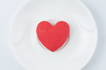 Valentines day background with modelling clay of red heart on a white plate.