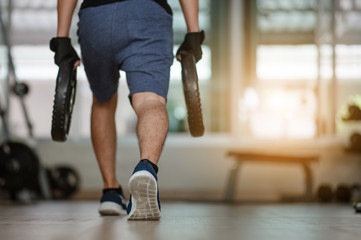 sport, bodybuilding, lifestyle and people concept - young man with Steel weights flexing muscles and making shoulder press lunge in gym