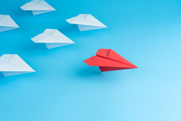 Leadership concept with red paper plane leading among white on blue background.