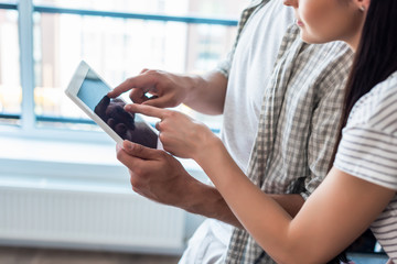 cropped shot of married couple using digital tablet together at home, smart home concept