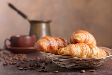 Fresh and tasty croissant  and cup of coffee on old copper background.