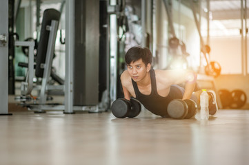 Fototapeta na wymiar Sport. Handsome man doing push ups exercise with one hand in fitness gym.Fitness instructor at the gym - Control your mind, conquer your body.Handsome muscular man is working out with dumbbells in gym