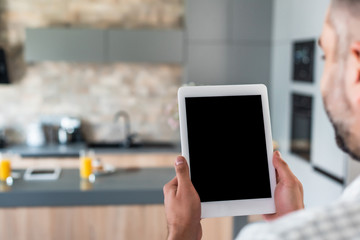 selective focus of man holding tablet with blank screen in hands in kitchen