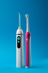 Toothbrush and irrigator with a floss cartridge on blue pastel background, close up vertical view