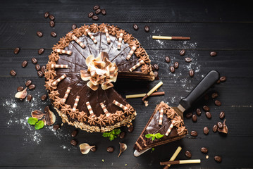 Sweet chocolate cake with tasty cream on the black wooden background