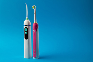 Toothbrush and irrigator with a floss cartridge on blue pastel background with copy space, close up view