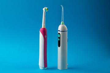 Toothbrush and irrigator with a floss cartridge on blue pastel background in center with copy space...