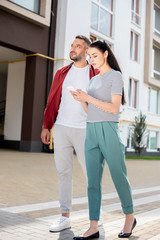 woman using smartphone while walking with husband on street