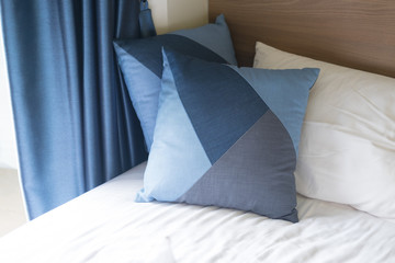 Blue pillows on sheets bed with blue curtain