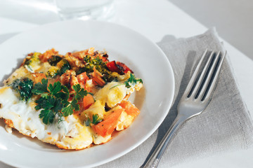 Scrambled eggs with tomatoes and greens on an white background