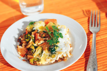 Scrambled eggs with tomatoes and greens on an orange background