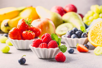 Fresh assorted fruits and berries on light gray background. Colorful clean and healthy eating. Detox food. Retro style toned.
