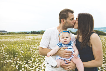 littlegirl and his father and mother enjoying outdoors in field of daisy flowers