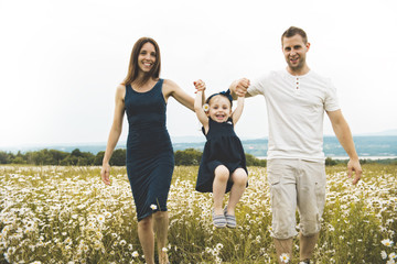 parent walking with her baby son on daisy field at the sunset time