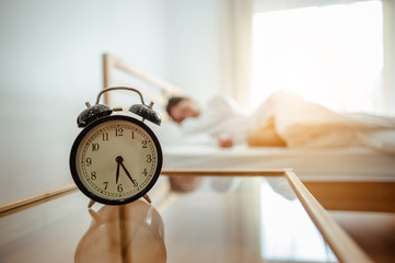 Closeup alarm clock  in bed after waking up, sunlight in morning.