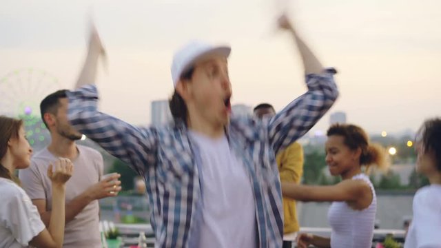 Sudden mood swing of handsome young man hipster standing outside with sad face then dancing happily with friends. Emotional change, partying and people concept.